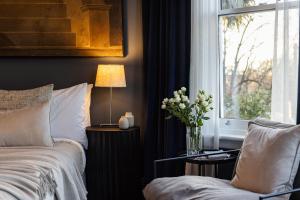 a bedroom with a bed and a window with a vase of flowers at Wahroonga on Bourke in Launceston