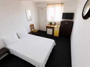 a bedroom with a white bed and a small desk at Casute tip A costinesti in Costinesti