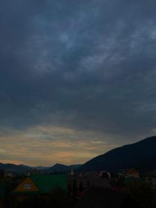 a cloudy sky over a city with mountains in the background at Старий Дуб in Mizhhirya +29 photos