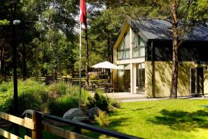 a house with a flag in the yard at Tago Forest - Dune Apartments in Jūrmalciems
