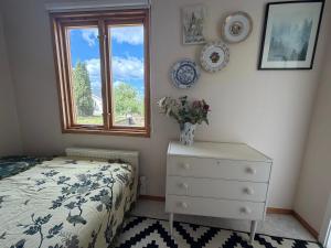a bedroom with a bed and a dresser and a window at Charmig Villa bredvid sjön Örlen in Tibro