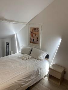 a bedroom with a white bed with a picture on the wall at Le Petit Canivet in Cerny