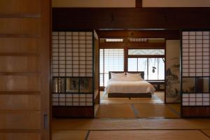 a bedroom with a bed in a room with windows at つむぎ in Shimoda