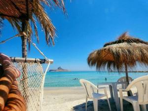 a table and chairs on a beach with the ocean at house in rafraf beach in Rafrāf