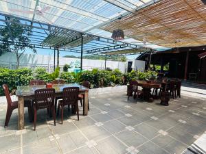 a patio with tables and chairs under a roof at Vital Point Kampot in Kampot