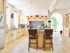 a kitchen with wooden cabinets and a island with bar stools at Kyre Park in Tenbury