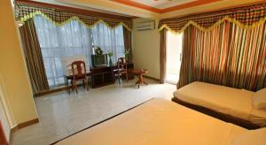 a bedroom with a bed and a desk with a television at Lucky Star Hotel in Phnom Penh