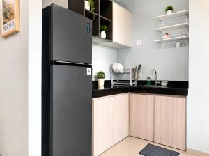a kitchen with a black refrigerator and wooden cabinets at Residencia Nova, Jakarta in Jakarta