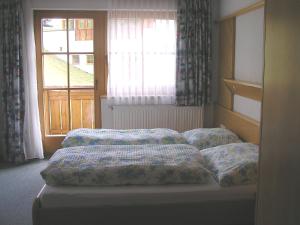 una cama con almohadas frente a una ventana en Haus Pinzger, en Fendels