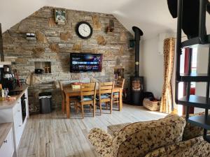 a dining room with a stone wall and a table and chairs at Dun Aengus Cottage on the Cliffs of Moher in Liscannor