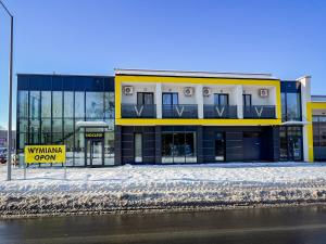 a yellow and white building with a sign in the snow at VENETIA-Rooms in Biecz