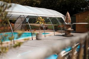 a deck with a white umbrella next to a pool at Happy Glamping in Wittelte