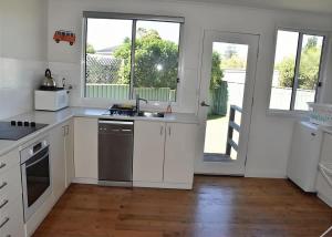 a kitchen with white cabinets and a large window at Barefoot Bungalow in Tomakin