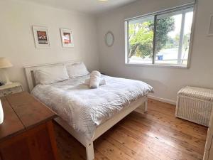 a bedroom with a white bed with a window at Barefoot Bungalow in Tomakin