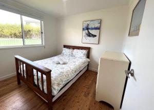 a small bedroom with a bed and a refrigerator at Barefoot Bungalow in Tomakin +3 photos