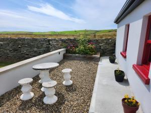 a patio with white stools and a stone wall at Dun Aengus Cottage on the Cliffs of Moher in Liscannor