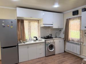 a kitchen with white cabinets and a washing machine at Moss House in Sevan