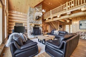 a living room with leather furniture and a stone fireplace at Fiddler Lake Resort - Moose 93 in Mille-Isles