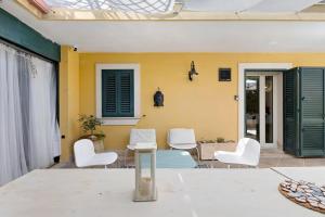 a patio with white chairs and a table at Villa Magda - private pool 20 pax in Marina di Ragusa