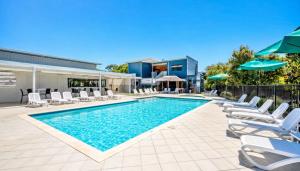 a swimming pool with lounge chairs and umbrellas at Townhouse 7 - Located at FOOTPRINTS PRESTON BEACH RESORT in Preston Beach