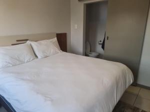 a bed with white sheets and pillows in a bedroom at Northview APARTMENTS SELF CATERING in Pretoria +4 photos