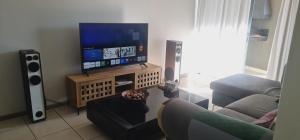 a living room with a flat screen tv and speakers at Northview APARTMENTS SELF CATERING in Pretoria