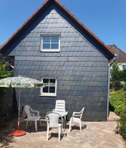 a blue house with chairs and a table and an umbrella at Historisches Ferienhaus Tönchen in Rinteln