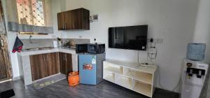 a kitchen with a refrigerator and a tv on the wall at Tulia Stays in Mtwapa