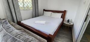 a bedroom with a bed with white sheets and a window at Tulia Stays in Mtwapa
