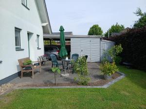 a patio with a table and a green umbrella at Ferienwohnung Auszeit mit Waldgeflüster 35231 in Hesel
