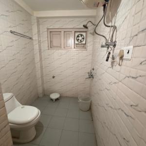 a white bathroom with a toilet and a window at Hotel Aman in Nārkanda