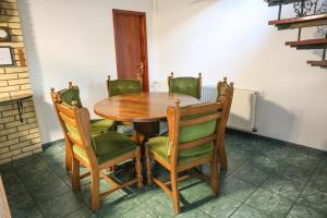 a dining room table with green chairs and a wooden table at Villa Ferra in Virovitica