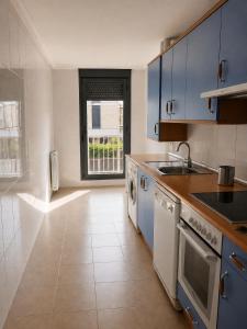 a large kitchen with blue cabinets and a window at El jardín de Cirueña in Cirueña +3 photos