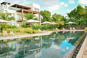 a swimming pool with chairs and umbrellas in front of a building at Ocean Point Beachfront Penthouses by Gerards & Angel in Pointe aux Piments