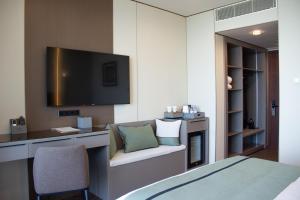 a room with a tv and a couch and a chair at Boutique Hotel 19D in Almaty