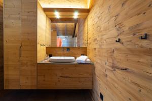 a bathroom with a sink in a wooden wall at Chalet Schibenstoll - Luxury & Bergblick in Wildhaus +21 photos