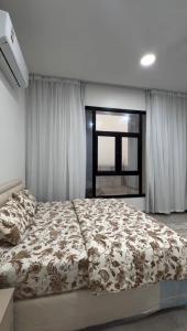 a bedroom with a bed with a comforter and a window at دوحة ظُفار للعقارات in Sumhuran +11 photos