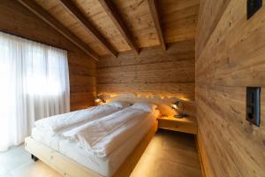 a bedroom with a bed and a wooden wall at Chalet Schibenstoll - Luxury & Bergblick in Wildhaus