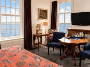 a hotel room with a bed and a television and a desk at de Campveerse Toren in Veere