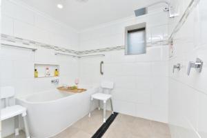 a white bathroom with a tub and a sink at Coal d' Vine Chillout - Cessnock NSW in Cessnock +10 photos