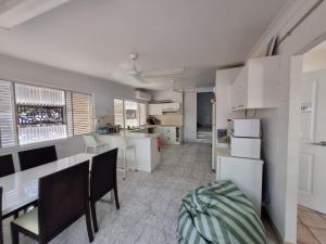 a kitchen with white appliances and a table and chairs at Backpackers Homestay 21-36 yrs ONLY in Caloundra