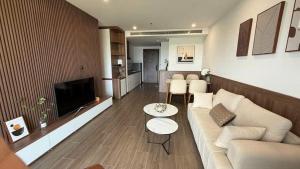 a living room with a white couch and a television at Khách Sạn L'AZUR in Cửa Lô