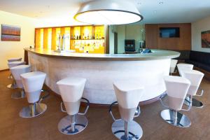 a bar with a row of white bar stools at Sercotel Valladolid in Valladolid