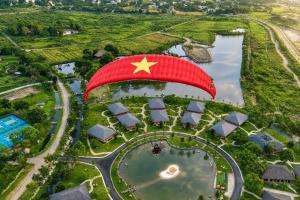 a red parachute with a star on it flying over a lake at Cuc Phuong Mineral Retreat in Ninh Binh