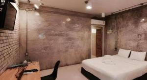 a bedroom with a large white bed and a desk at The State Resort in Ban Wat Phrik (1)