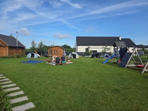 a group of people sitting in a yard with a playground at Pole biwakowe U Marcina in Kwidzyn