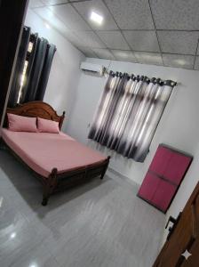 a bedroom with a bed with pink sheets and a window at CeylonAirbnb in Puttalam