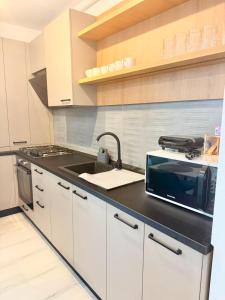 a kitchen with a sink and a microwave at DOCA Apartments 8 in Otopeni +1 photo