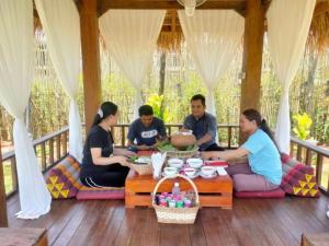 a group of people sitting around a table on a porch at Kampot Tropical Resort 