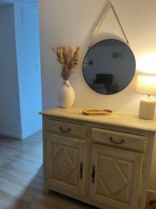 a dresser with a mirror and a vase on it at Lamaisondubois31 in Pibrac